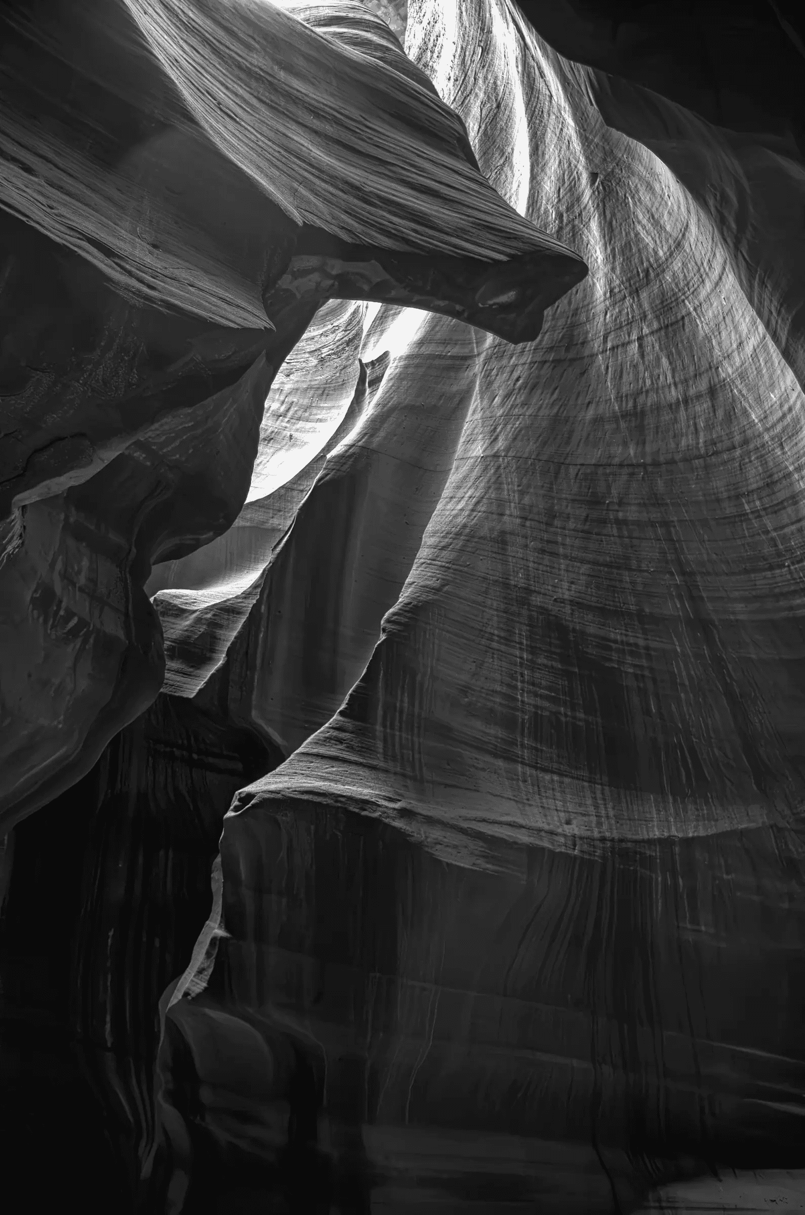 Carved Light, Antelope Canyon Interior of Antelope Canyon slot canyon showing striated sandstone walls folded around a bright shaft of light, rendered in black-and-white.