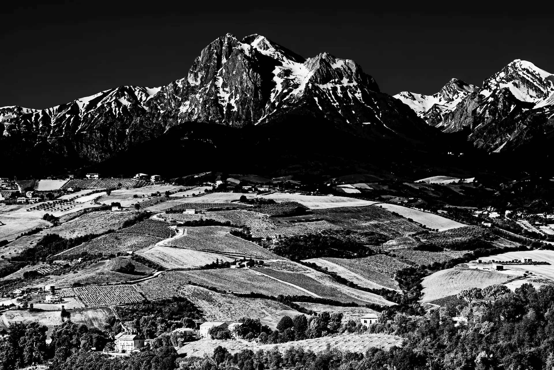 Black and white view of the Gran Sasso range above rolling hills in Italy.