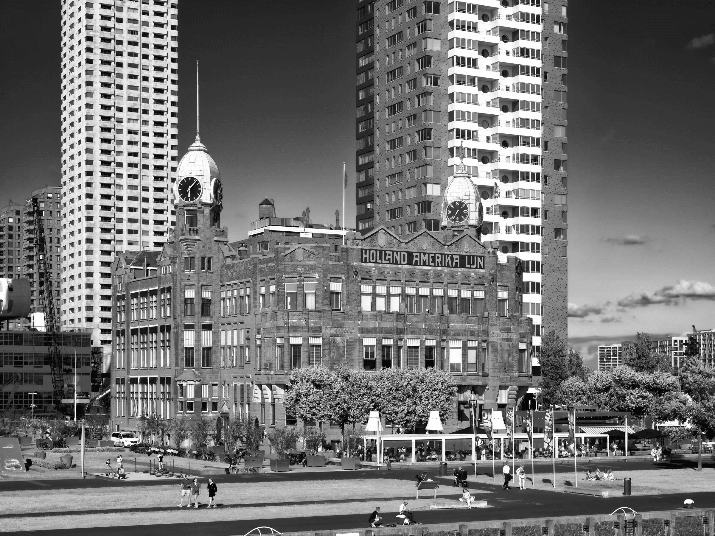 Holland-Amerika building in Rotterdam framed by towers above a public lawn.
