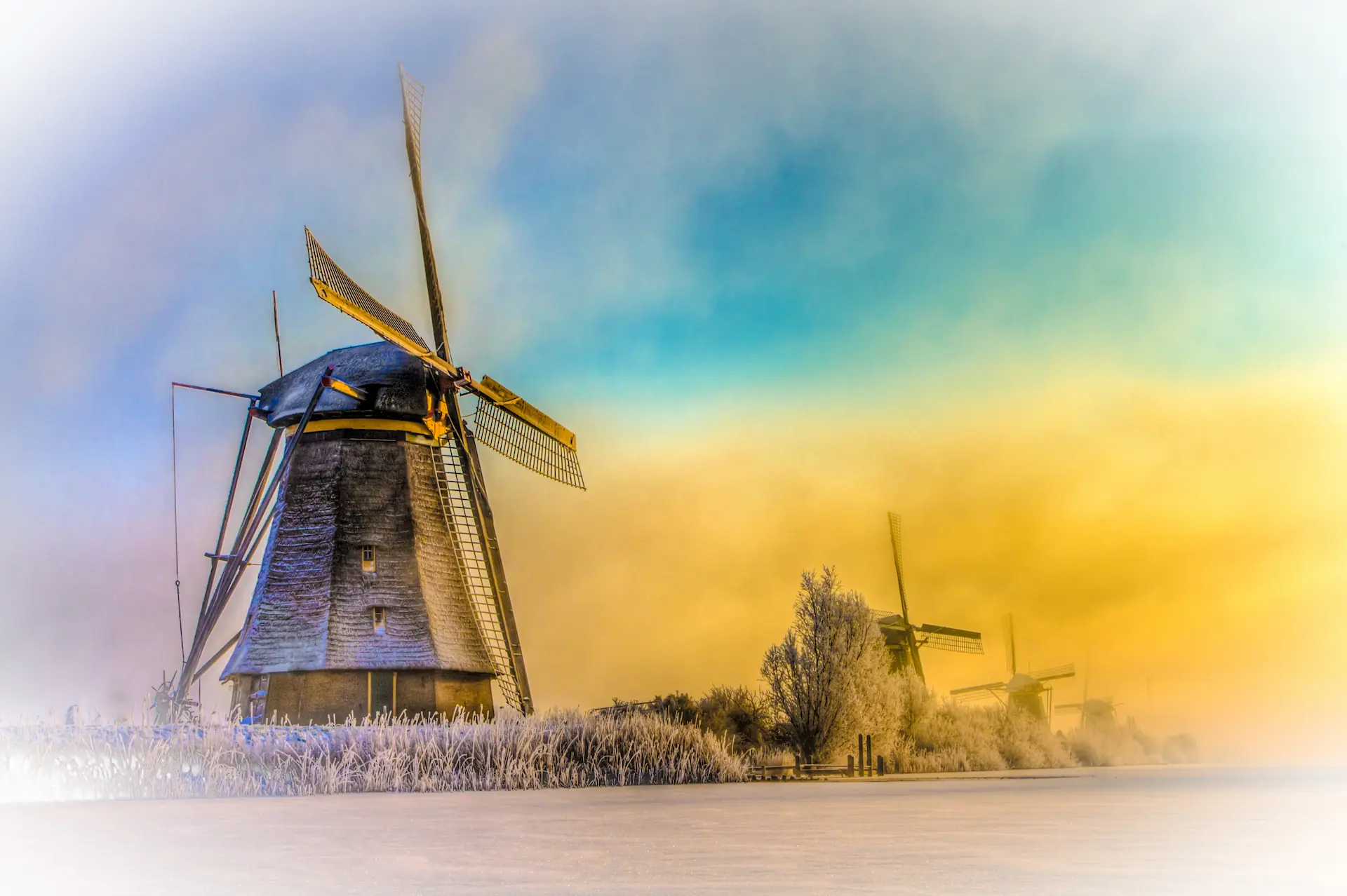Kinderdijk windmills under pastel winter light above frost-covered Dutch fields.