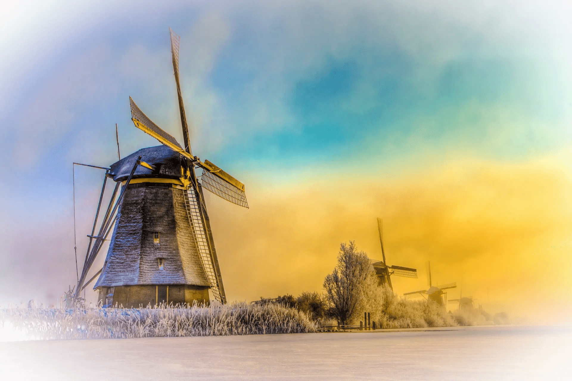 Kinderdijk windmills under pastel winter light above frost-covered Dutch fields.