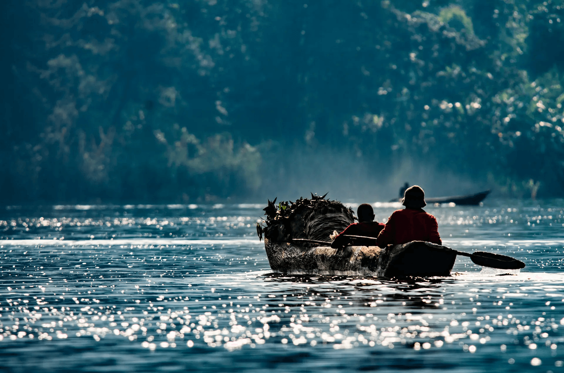 Traditional boat crossing shimmering water on Lake Bunyonyi, Uganda.