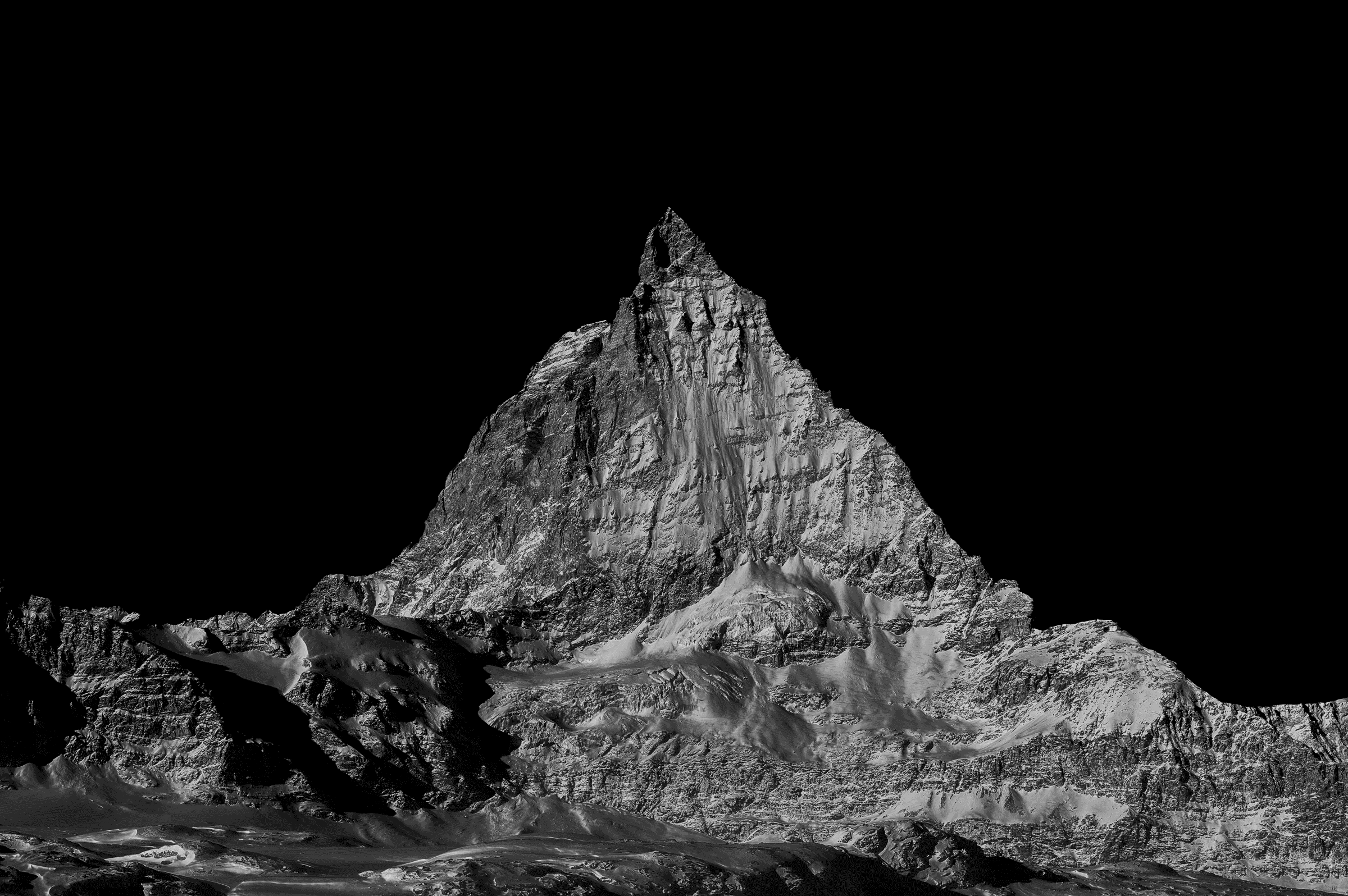 Dramatic black and white photograph isolating the iconic, snow-dusted peak of the Matterhorn against a dark sky.