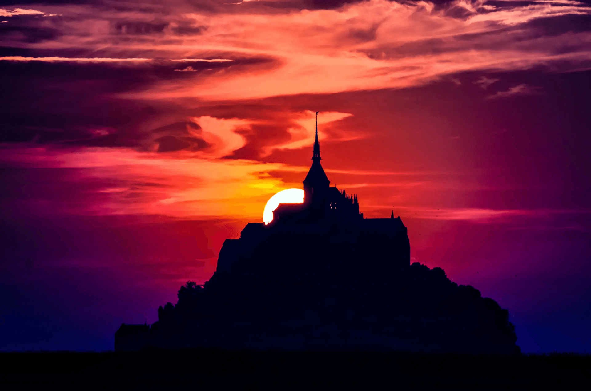 Silhouette of Mont Saint-Michel, France, at sunset.