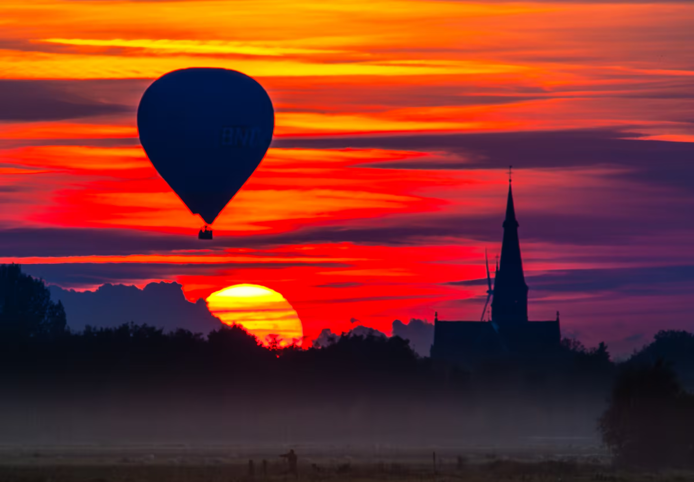 A hot air balloon silhouetted against a vibrant sunset in North Brabant, Netherlands.