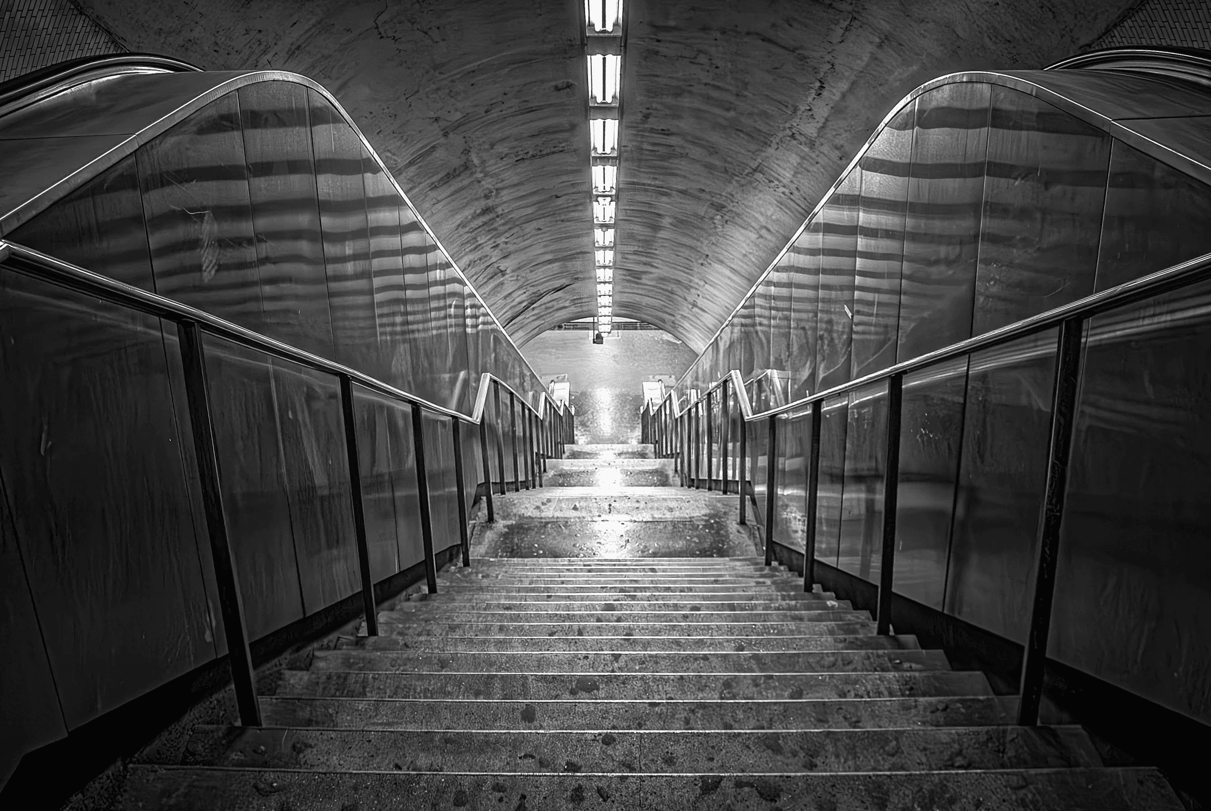 Click to view in fullscreen A long, empty staircase descending into a subway station.