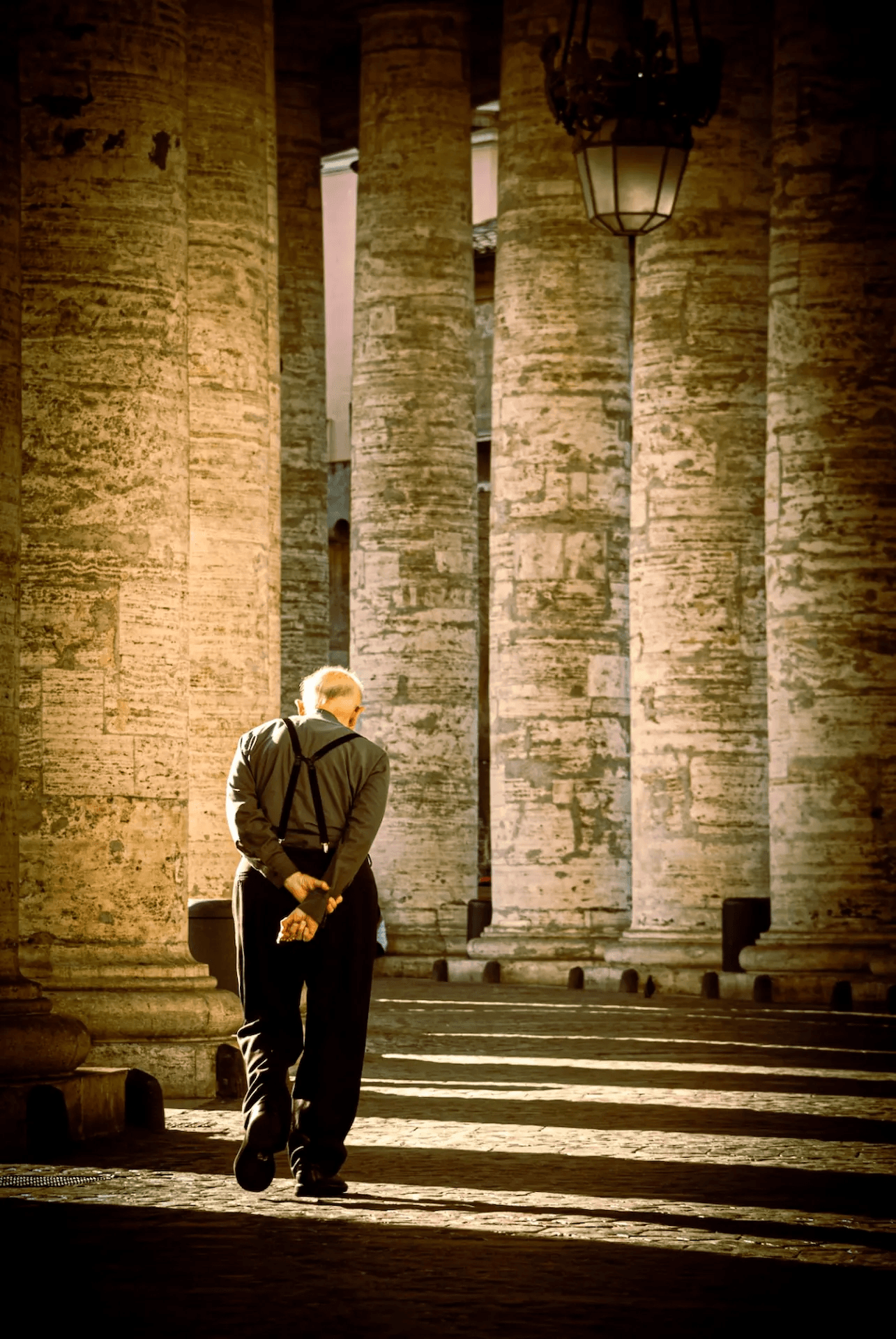 Priest walking beneath the colonnade of St. Peter's in Vatican City.