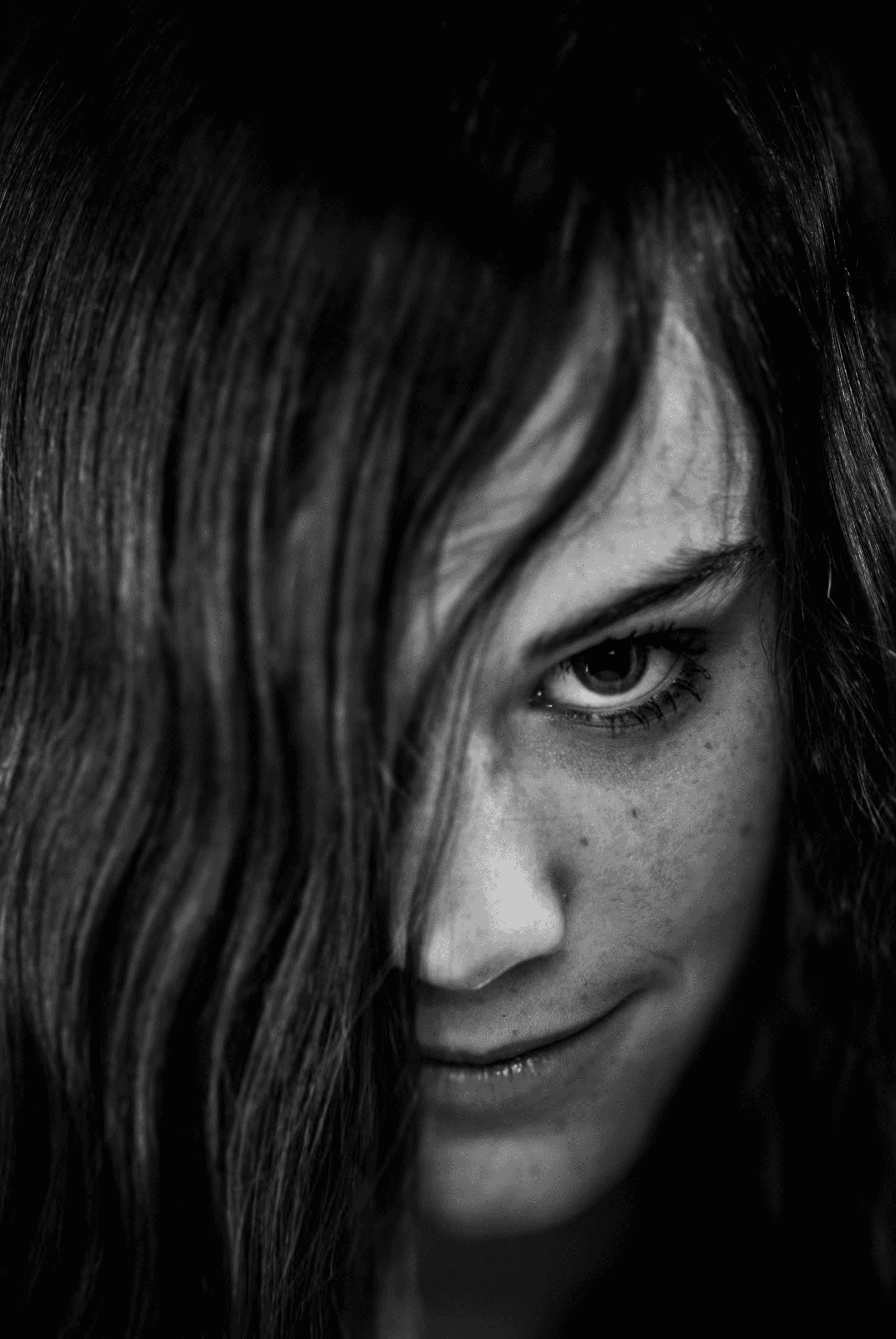 Black and white portrait of a woman with long hair partially covering her face.